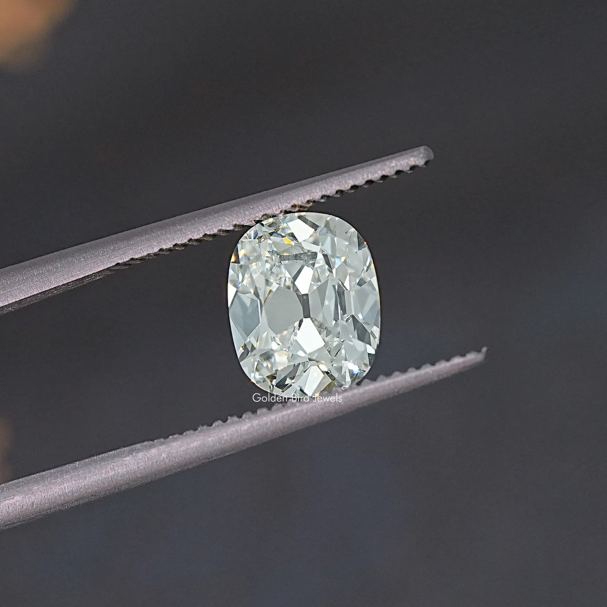 Old Mine cut lab-grown diamond close-up between tweezers, rounded cushion face.