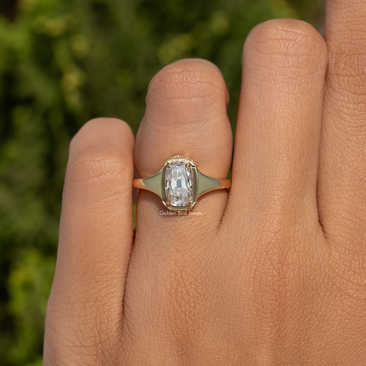 Elongated cushion-cut moissanite ring on hand with slim gold-toned band and halo