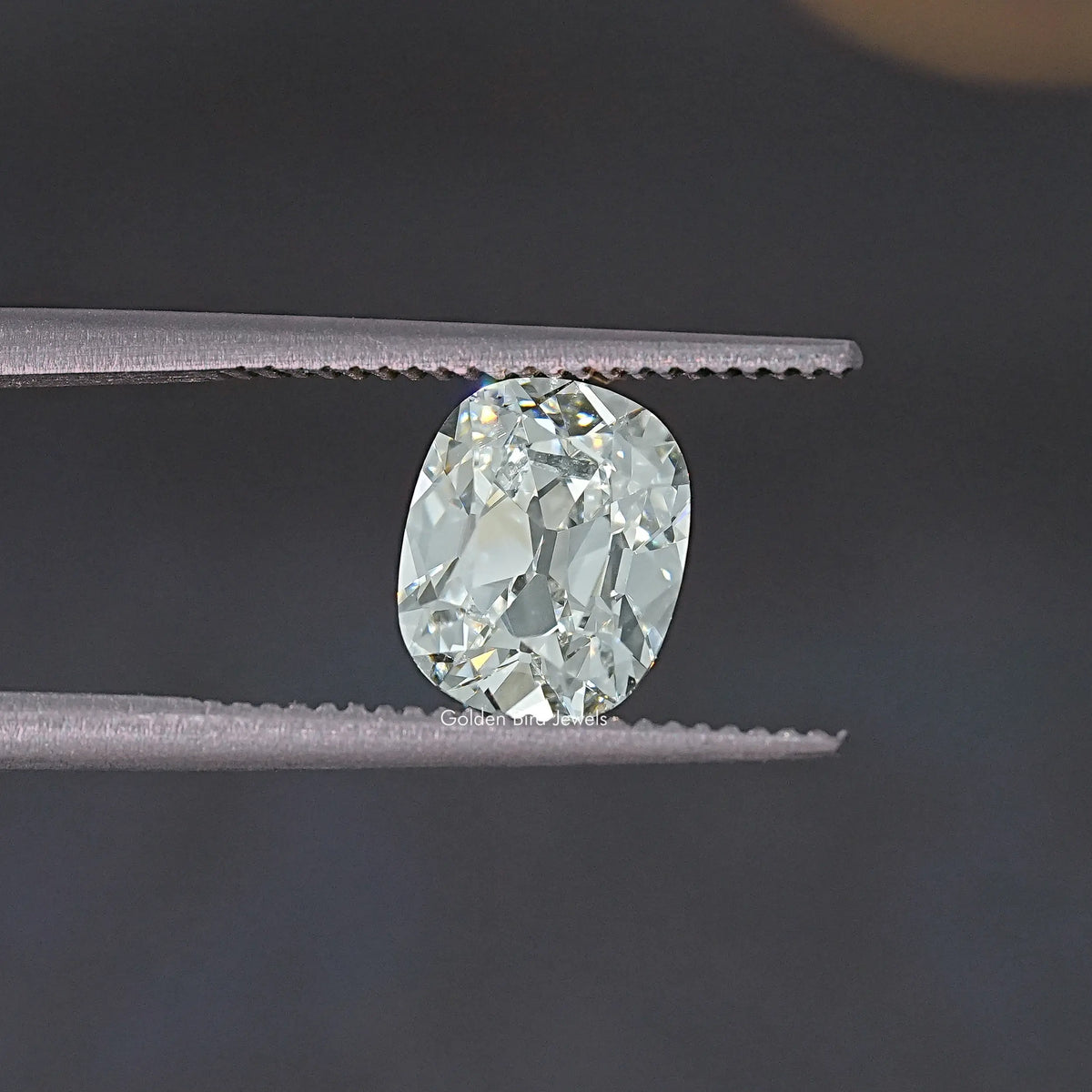 Old Mine cut lab-grown diamond view between tweezers, oval cushion facets.