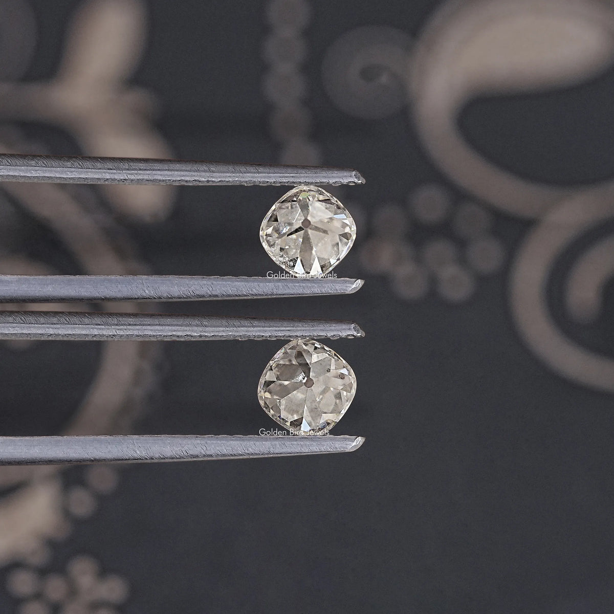 Loose cushion-cut moissanite stones, clear, two stones shown on metal prongs