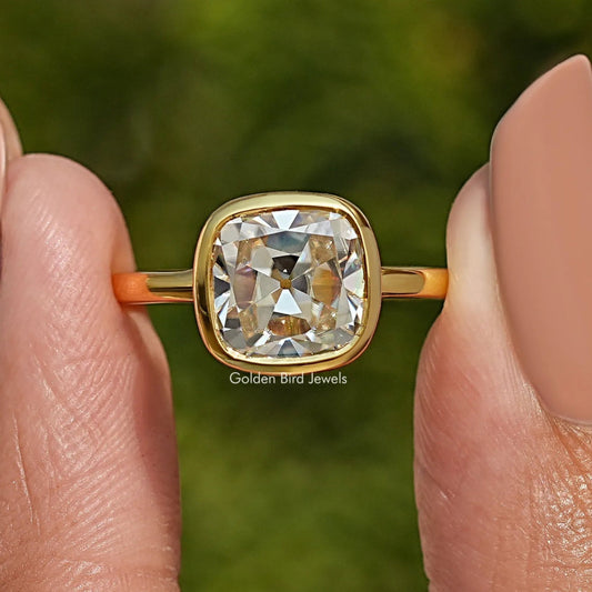 Close-up of gold bezel-set moissanite solitaire ring with square cushion center stone