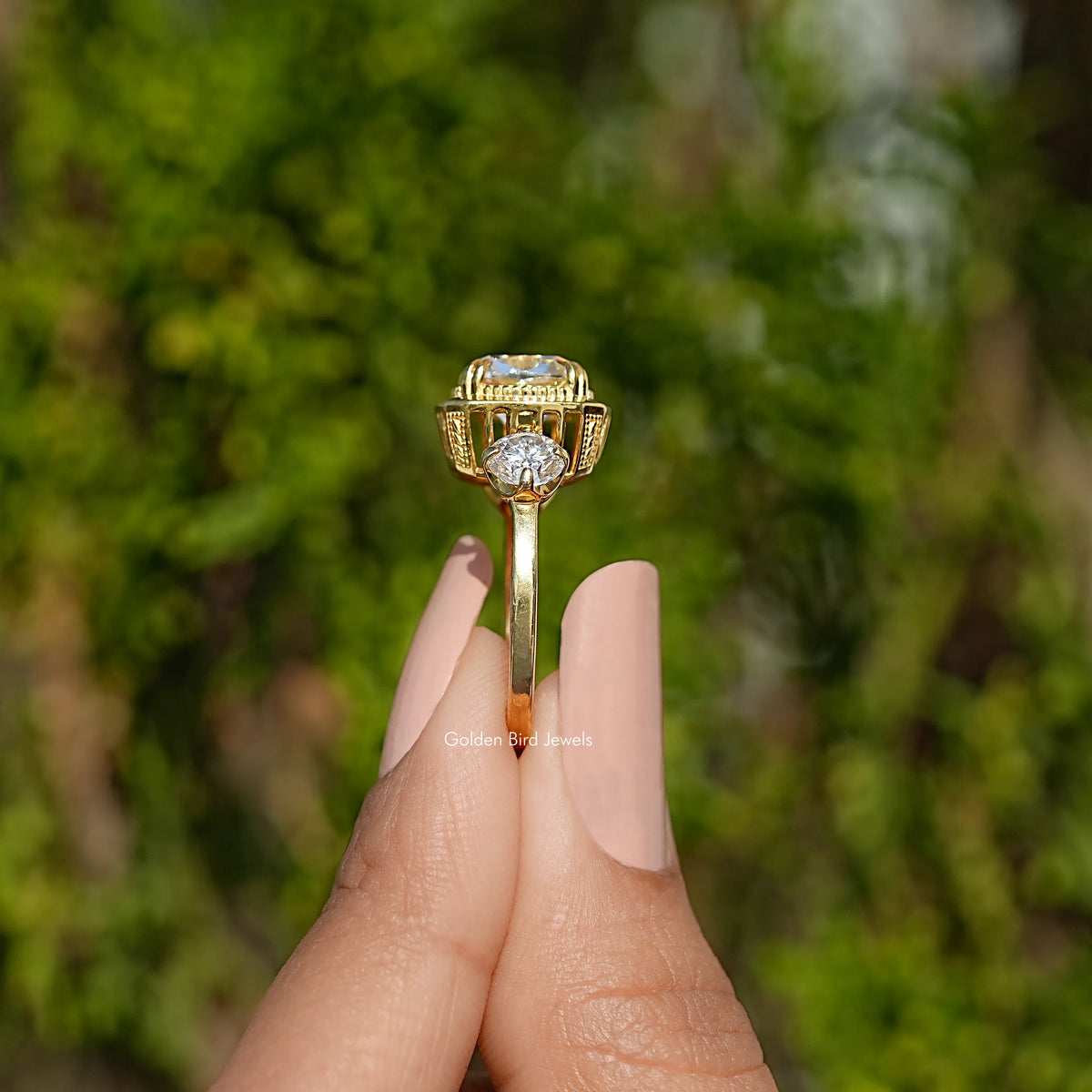 Three-stone cushion moissanite ring on finger, yellow gold tone, halo center