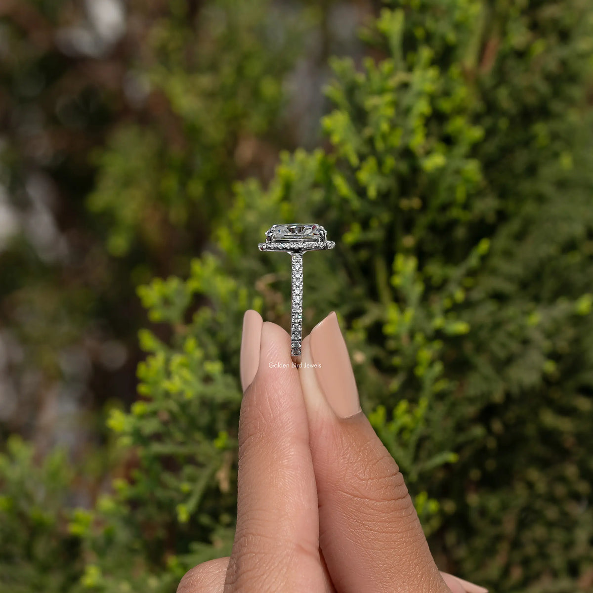Top view of halo cushion-cut moissanite engagement ring, prong setting on finger