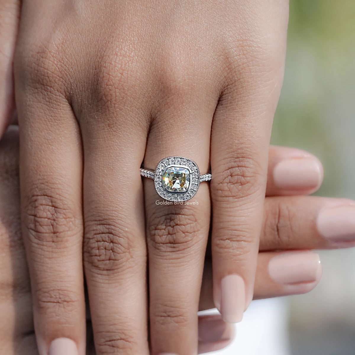 Moissanite cushion halo engagement ring on hand with pavé band
