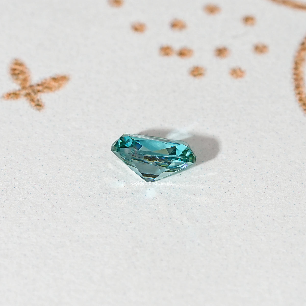 Blue-green cushion-cut moissanite gemstone shown at an angle, loose faceted stone.