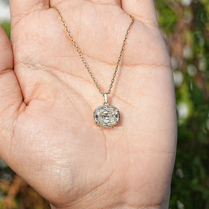 Cushion-cut moissanite pendant on gold chain held in open palm