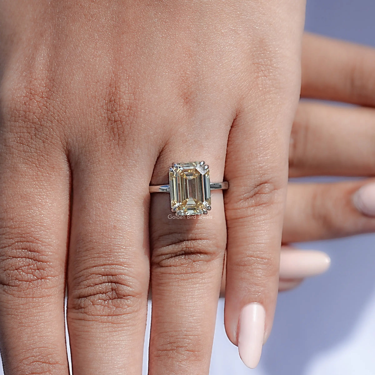 Emerald-cut moissanite solitaire ring close-up on hand, silver band and stone