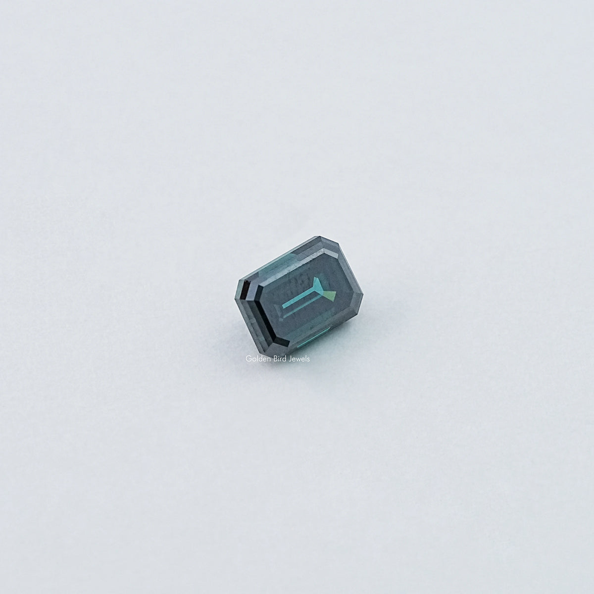 Loose emerald-cut dark green moissanite gemstone, side view of faceted facets