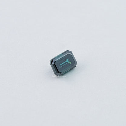 Loose emerald-cut dark green moissanite gemstone, side view of faceted facets