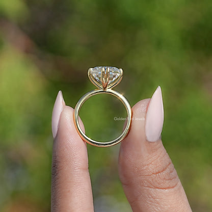 Side view of gold-tone solitaire ring with emerald-cut clear stone