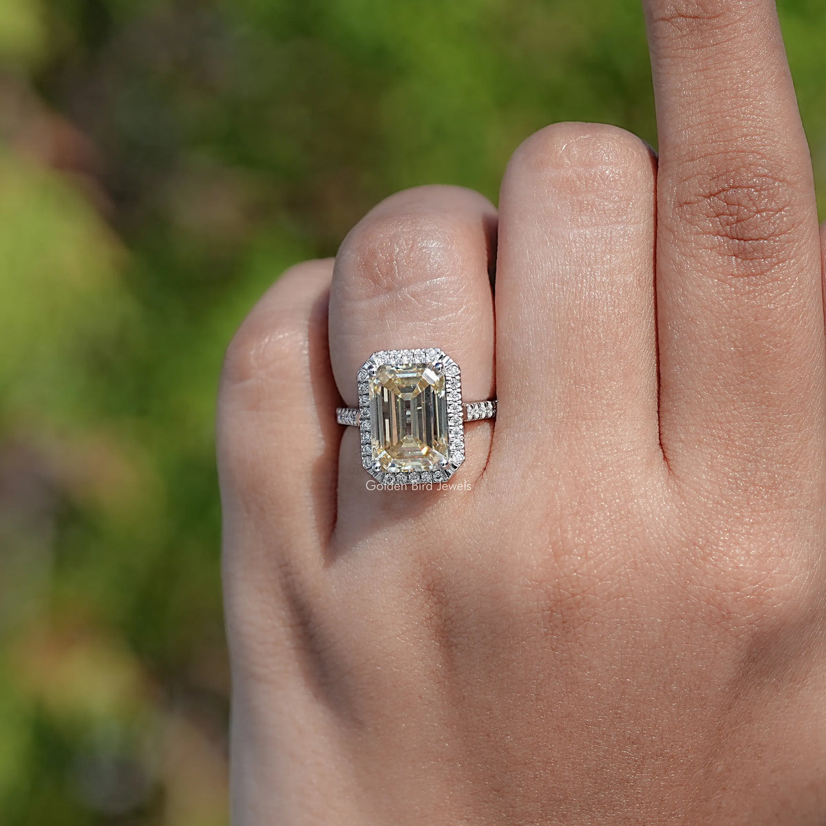 Emerald-cut moissanite halo accent ring on a finger