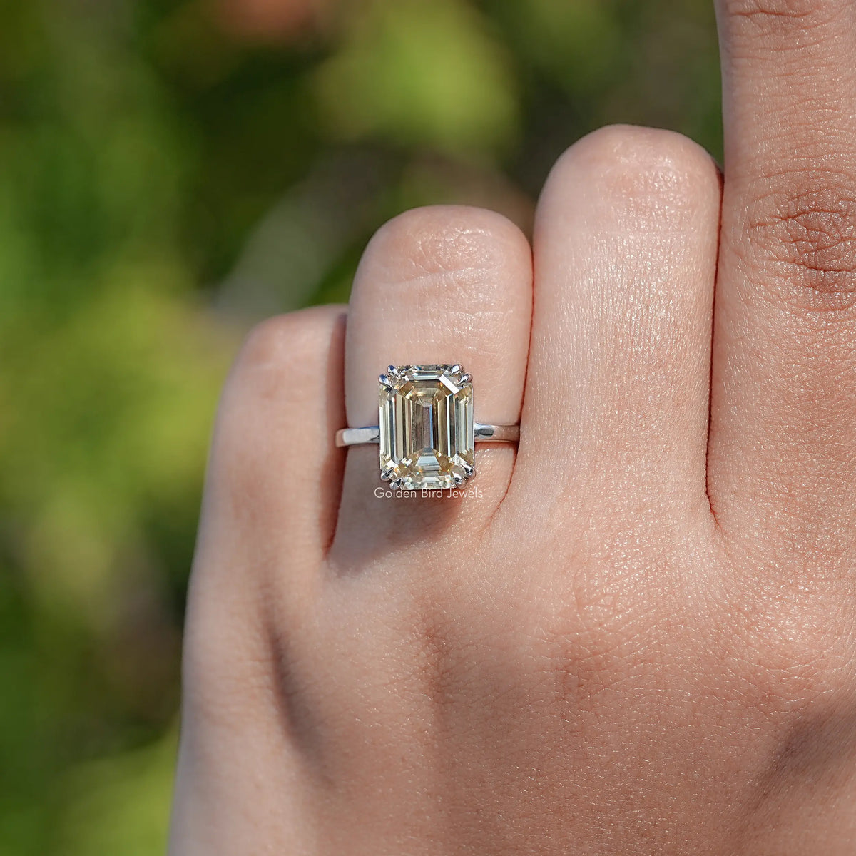 Emerald-cut moissanite solitaire ring, side view on hand with silver band