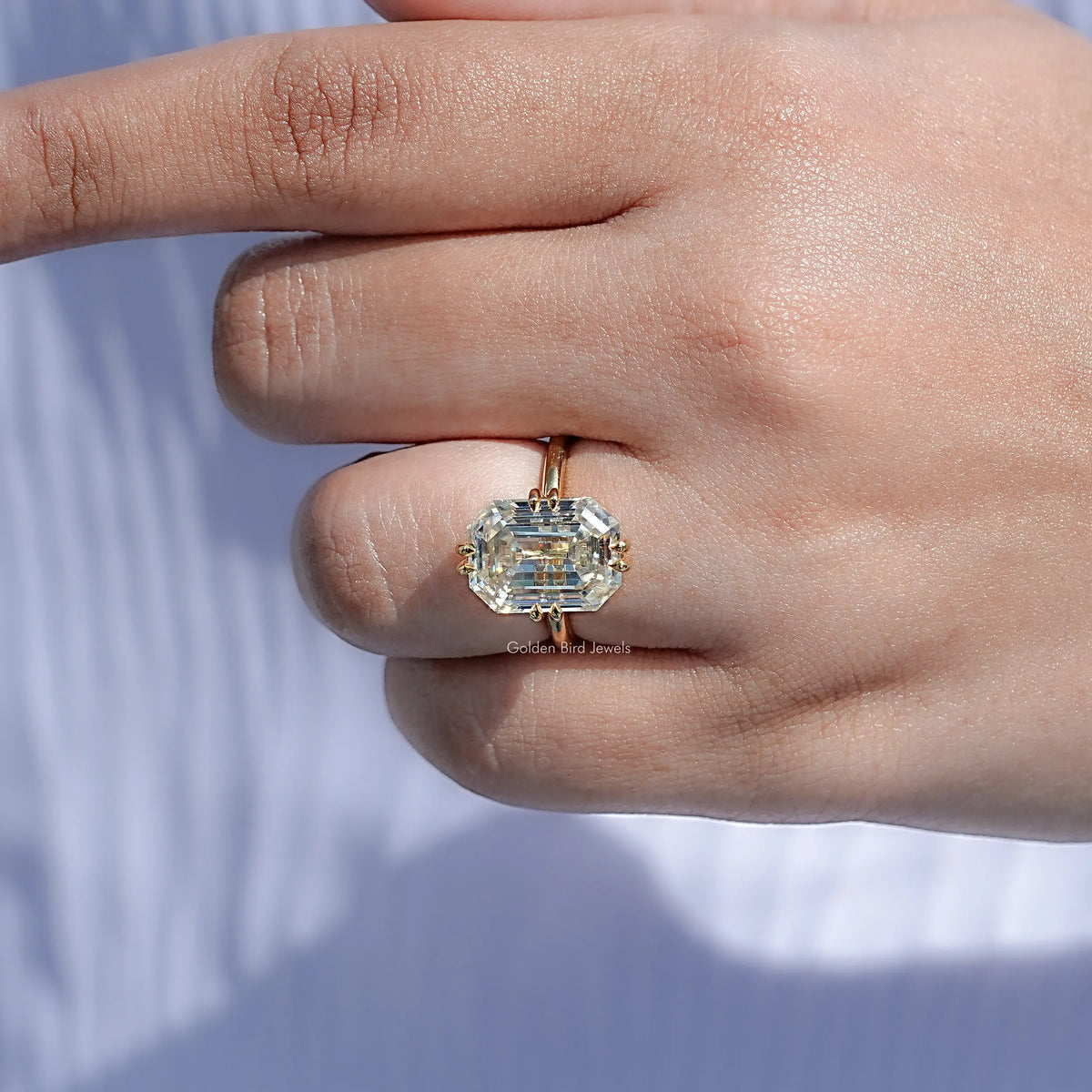 Gold-tone solitaire engagement ring with emerald-cut clear center stone