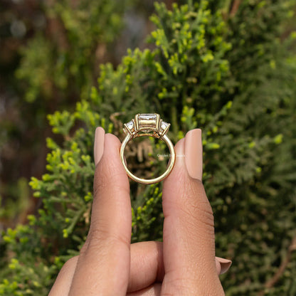 Three-stone emerald-cut moissanite ring viewed from the back, gold-tone setting.