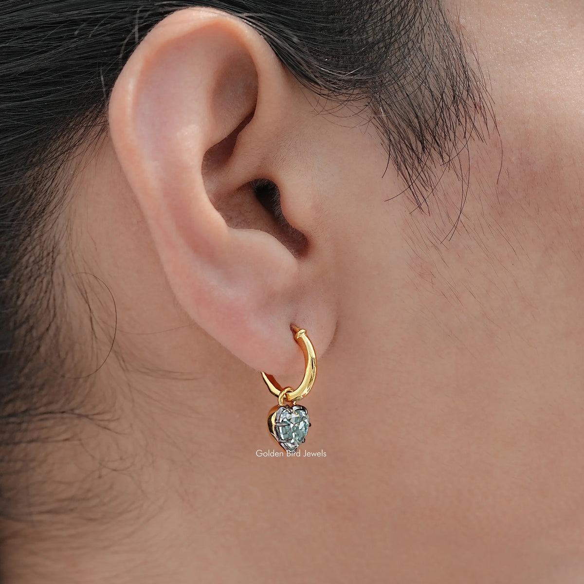 Gold hoop-style earrings with blue faceted gemstone dangles
