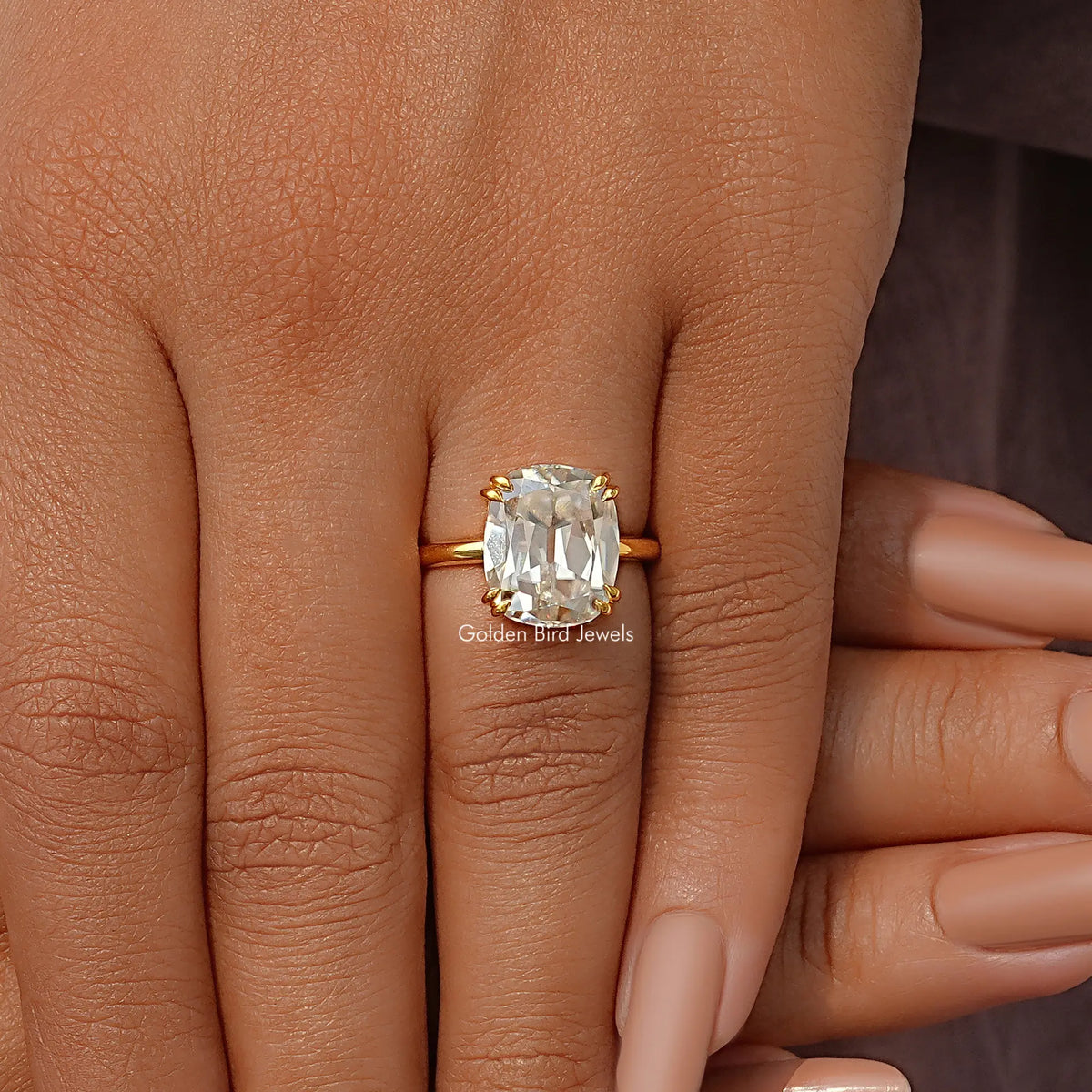 Gold-tone elongated cushion-cut solitaire ring with square center stone, close-up