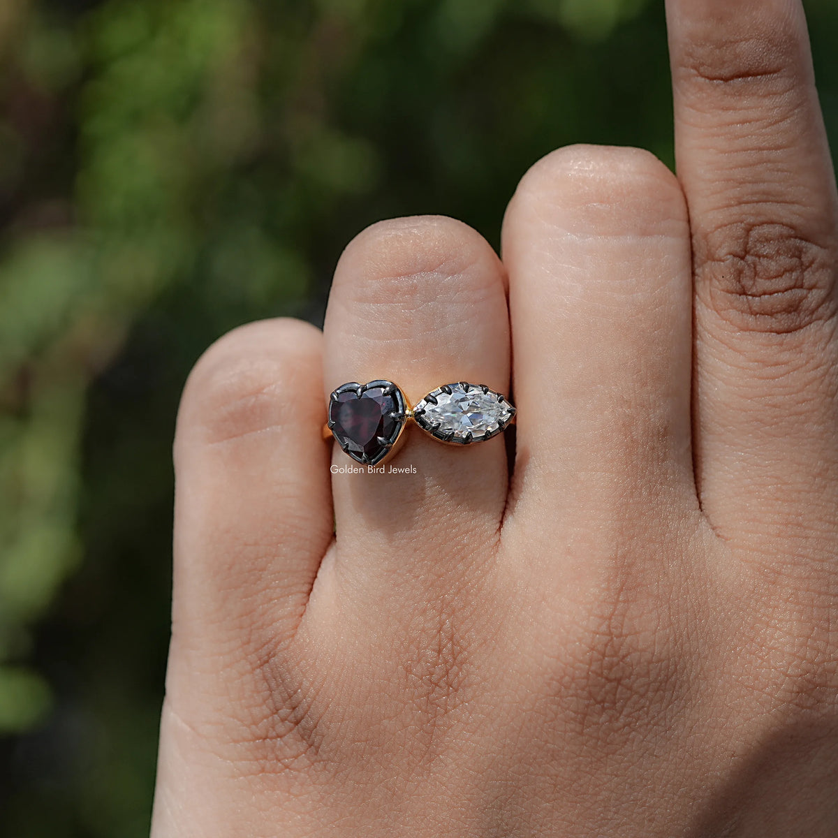 Heart two-stone ring on hand: dark heart gemstone and oval clear stone, silver-toned band