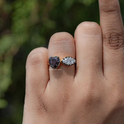 Heart two-stone ring on hand: dark heart gemstone and oval clear stone, silver-toned band