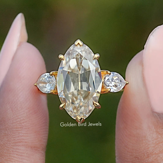 Three-stone pear moissanite ring with round side stones, gold-tone prongs