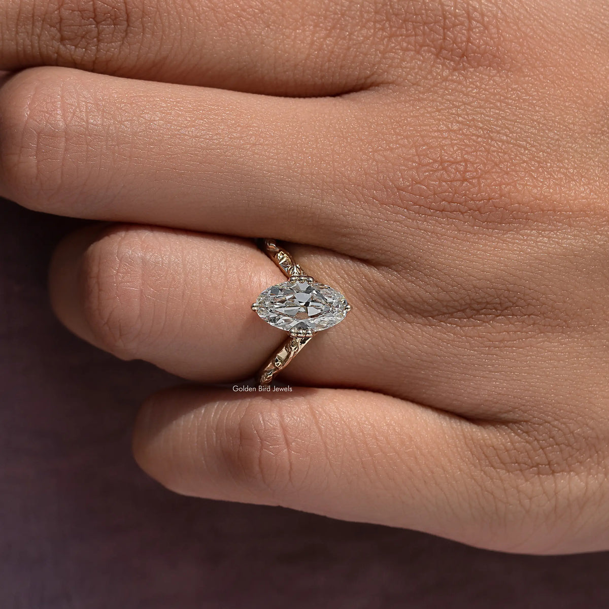 Oval diamond center ring with gold-tone twisted side details, close-up
