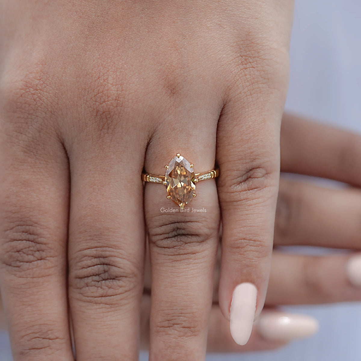 Gold-tone ring with oval amber center stone and small side stones, on finger