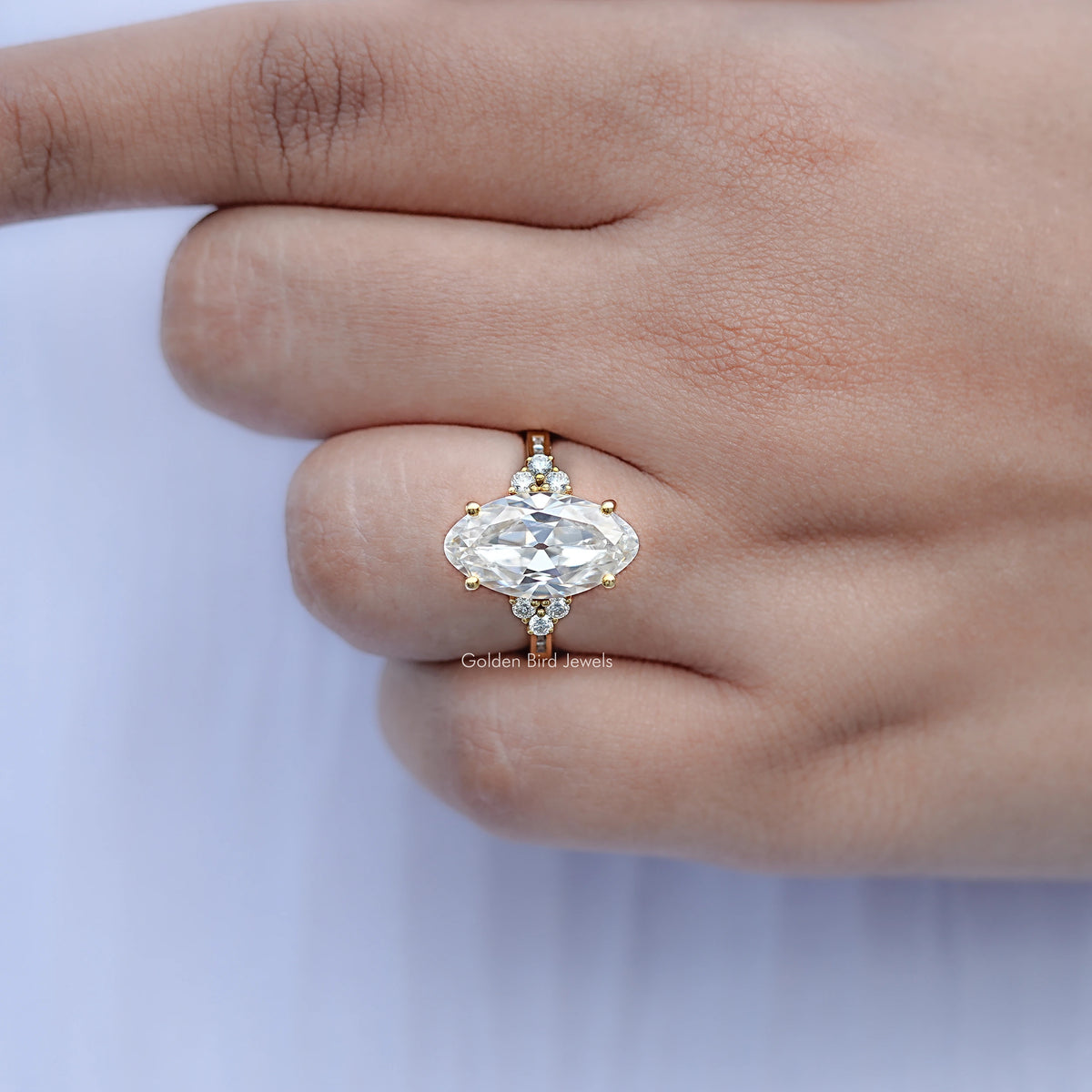 Oval moissanite ring with round side accents, close-up on relaxed hand