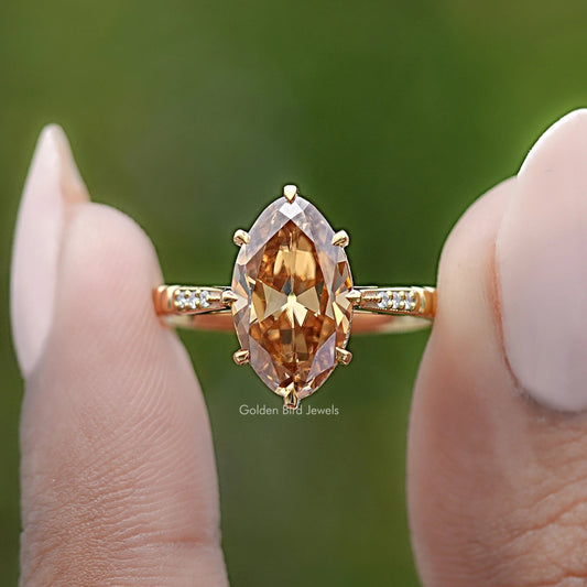 Gold-tone ring with oval amber center stone and small baguette side stones, close-up