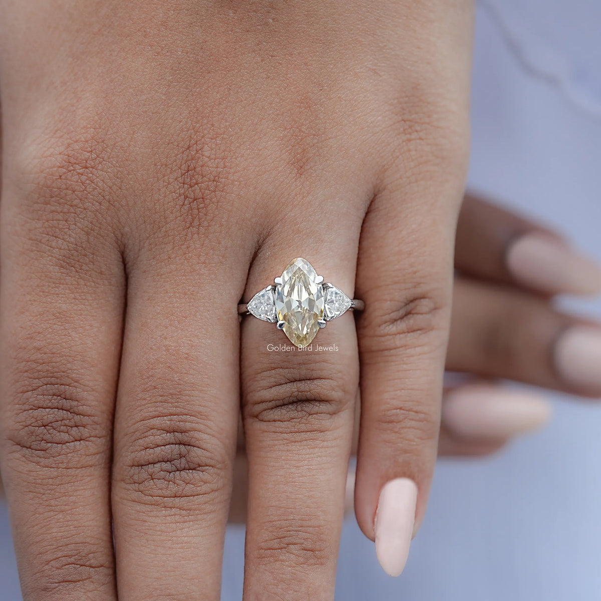 Three-stone moissanite ring on hand, central marquise stone with two side stones