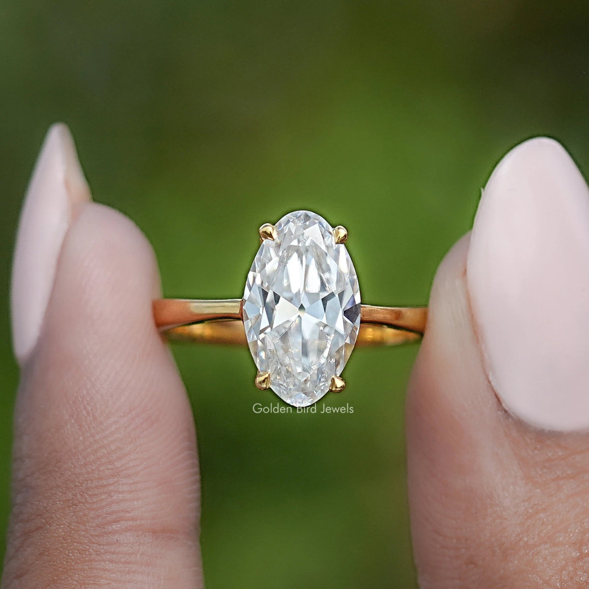 Gold oval moissanite ring with hidden halo, centered front view