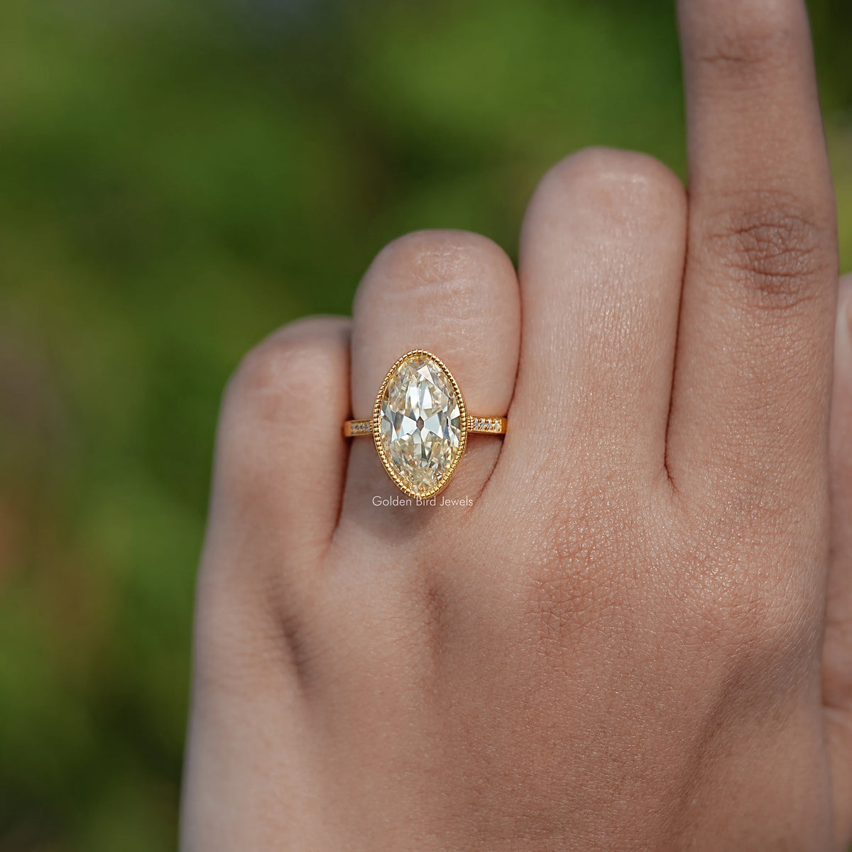Gold oval centerpiece moissanite ring with thin band and milgrain edge