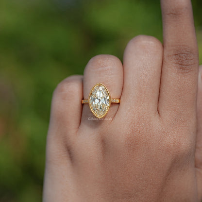 Gold oval centerpiece moissanite ring with thin band and milgrain edge