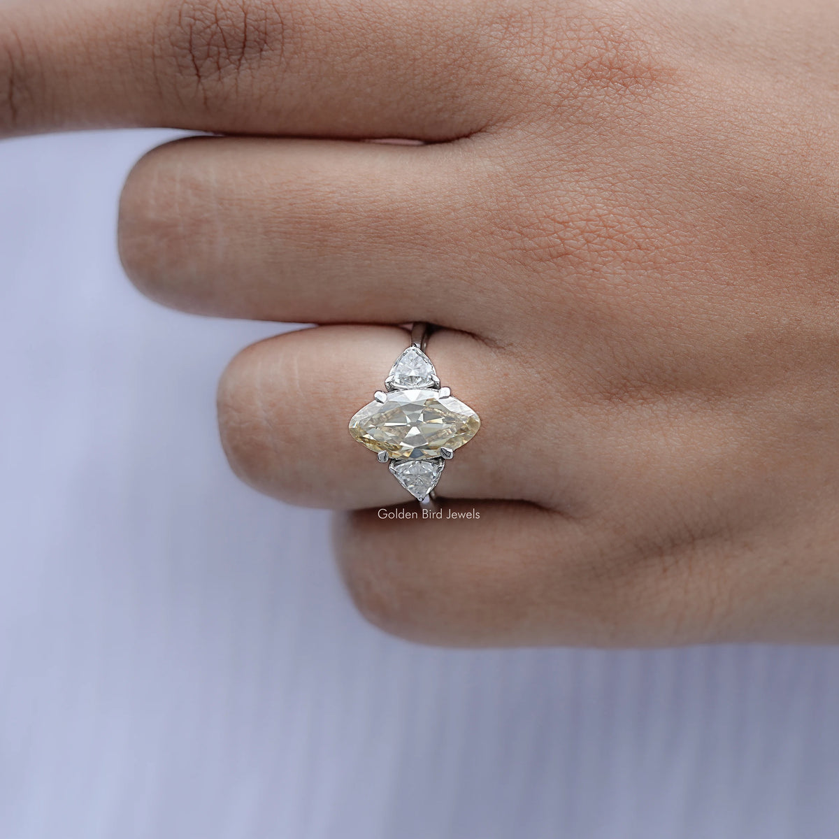 Three-stone ring with central marquise stone and two round side stones, close-up