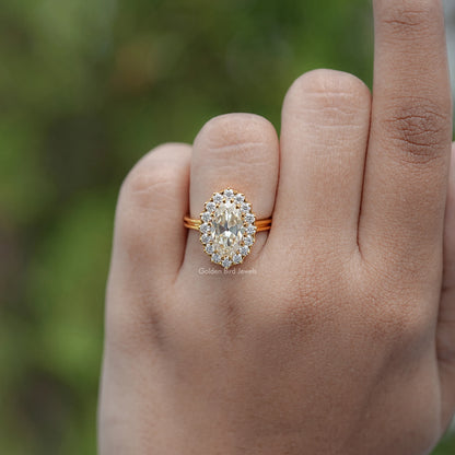 Gold-tone oval moissanite halo engagement ring on hand, close-up