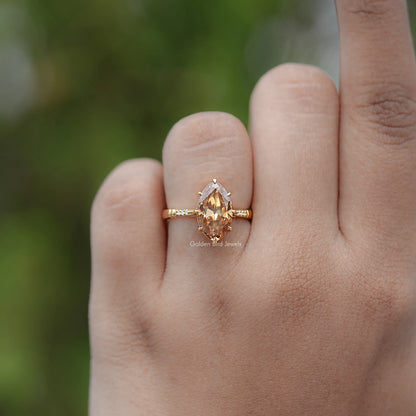Gold-tone ring with oval amber center stone on thin band, side view on finger