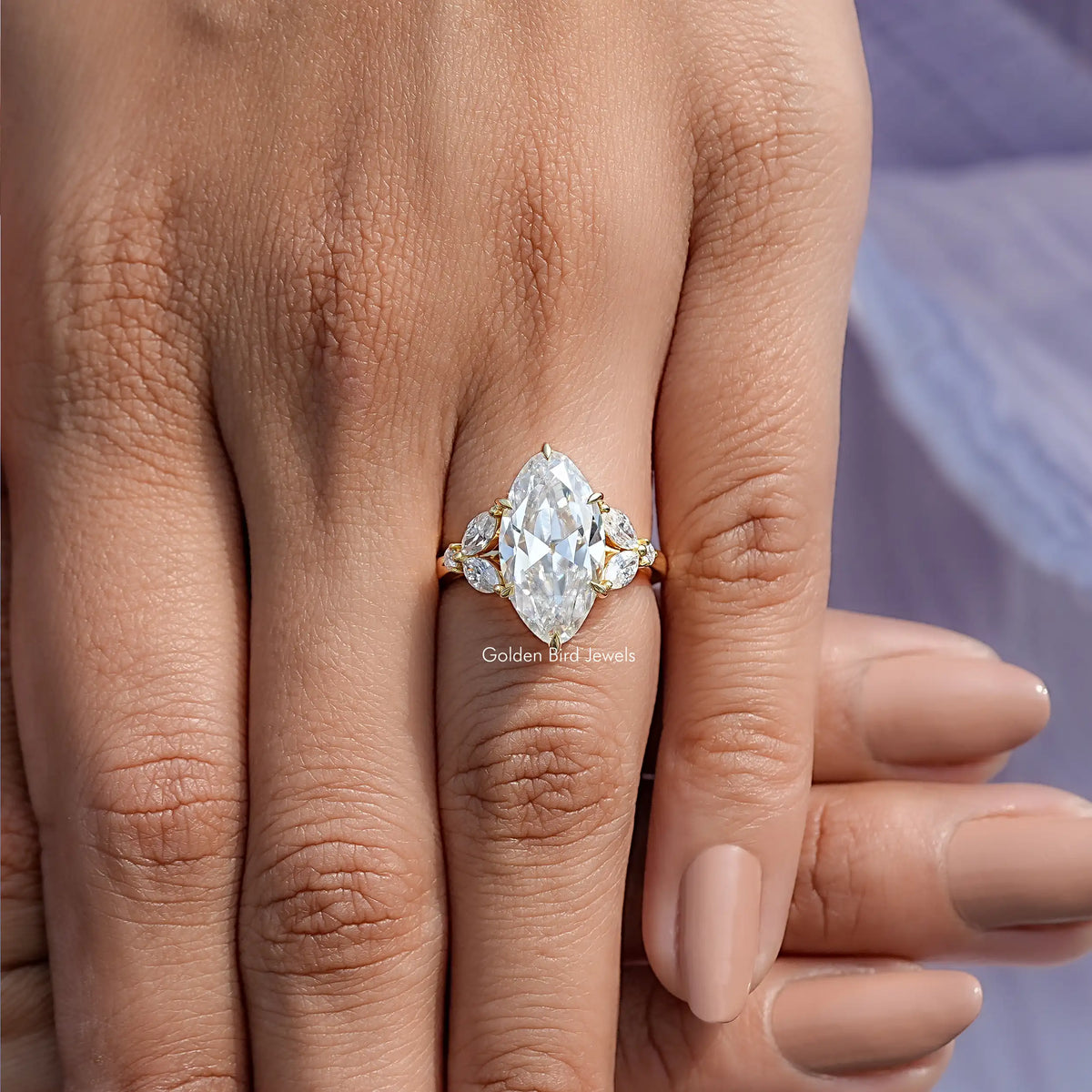Oval-cut moissanite engagement ring on hand, yellow gold-tone band with side stone accents