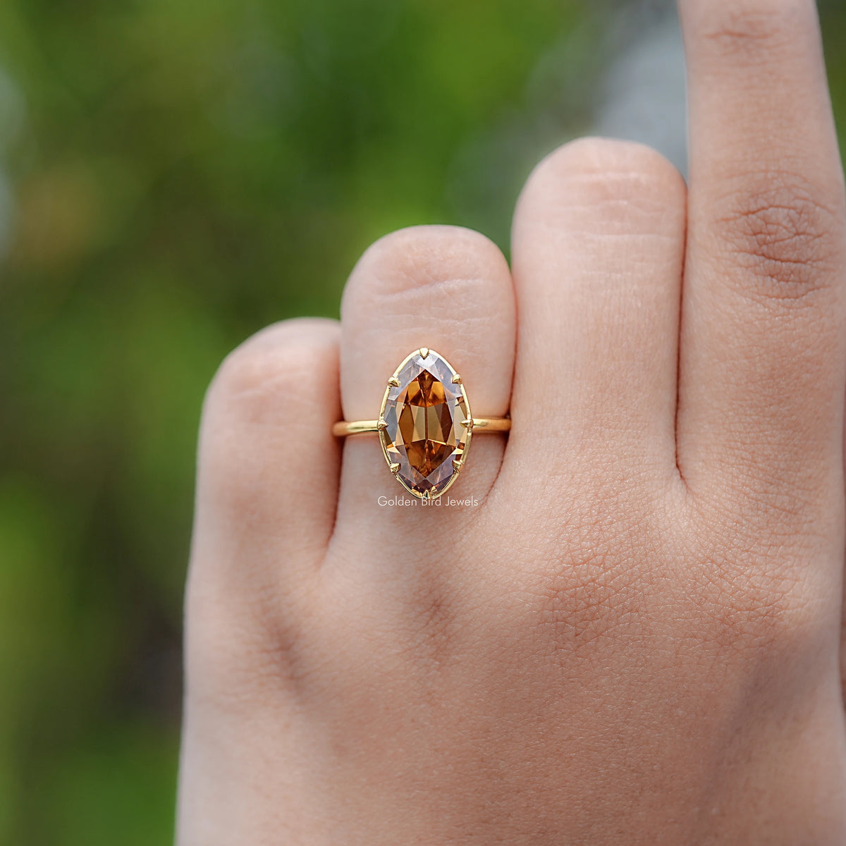 Gold-tone oval champagne solitaire ring with prong-set center stone, close hand view