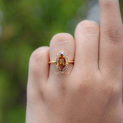 Gold-tone oval champagne solitaire ring with prong-set center stone, close hand view