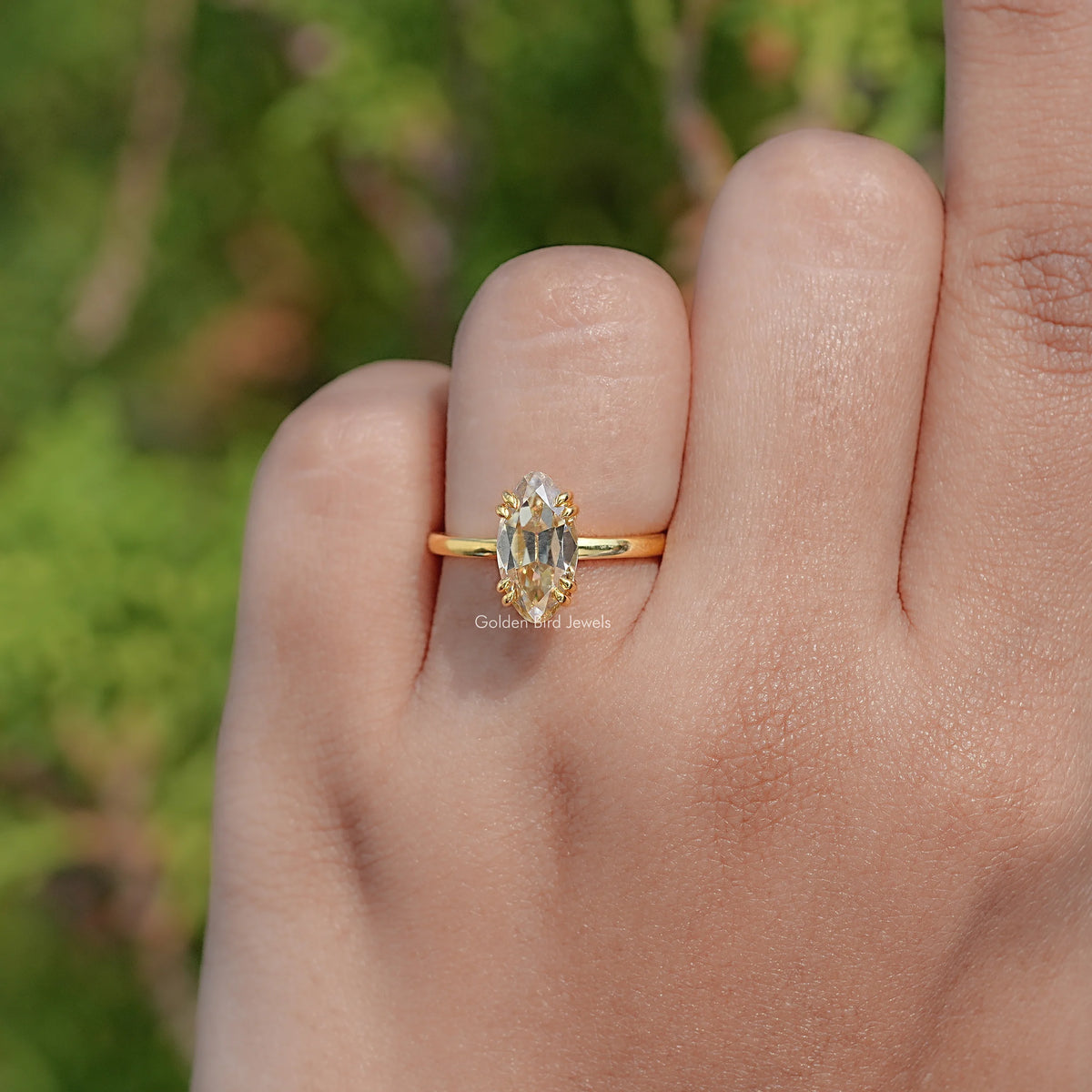 Gold solitaire ring on finger, oval center stone with prongs and slim band