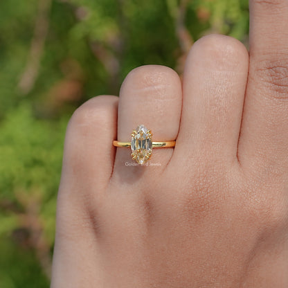 Gold solitaire ring on finger, oval center stone with prongs and slim band