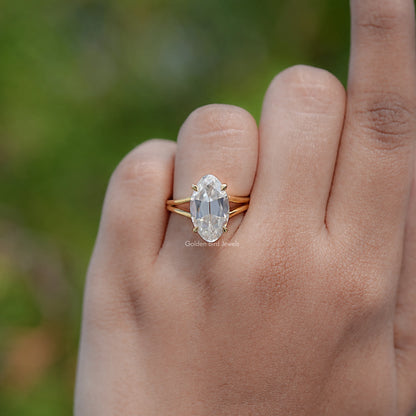 Gold moissanite solitaire ring, oval center stone and split shank on hand