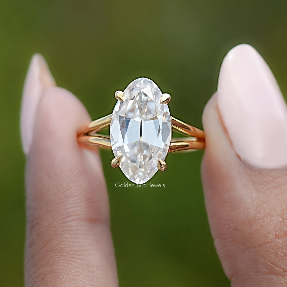 Gold moissanite solitaire ring, oval center stone, split shank on finger