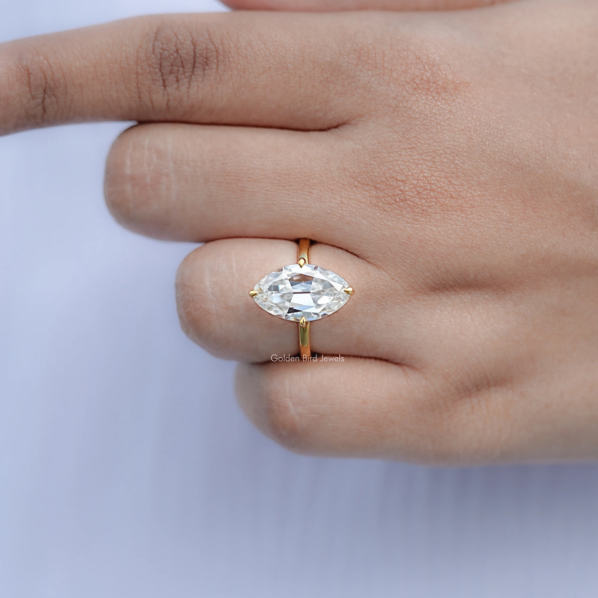 Gold moissanite solitaire ring close-up, oval center stone on slim band