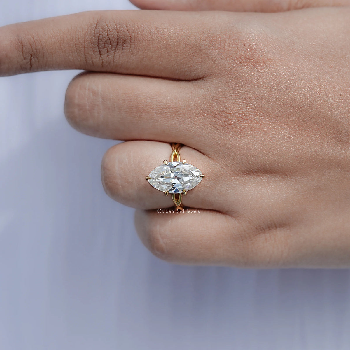Gold-tone oval solitaire ring with prongs, close-up on finger