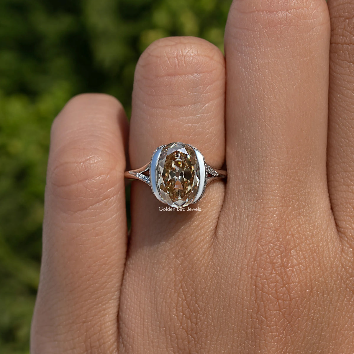 Silver oval-cut engagement ring on hand with half bezel setting and side accents