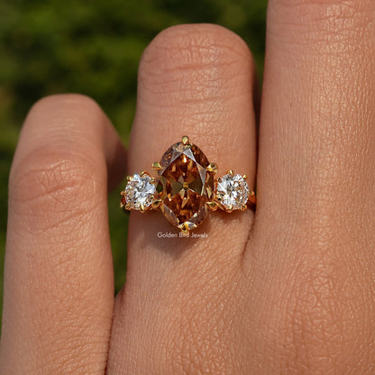 Three-stone engagement ring: oval brown center with two round side stones