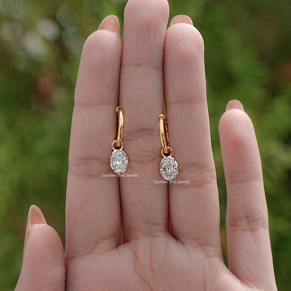 Gold-tone hoop dangle earrings with oval-cut moissanite stones, front view