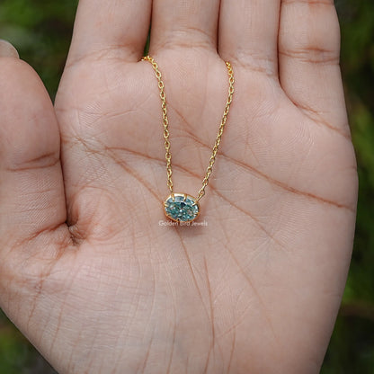 Gold-tone oval moissanite pendant necklace on open palm with blue center stone