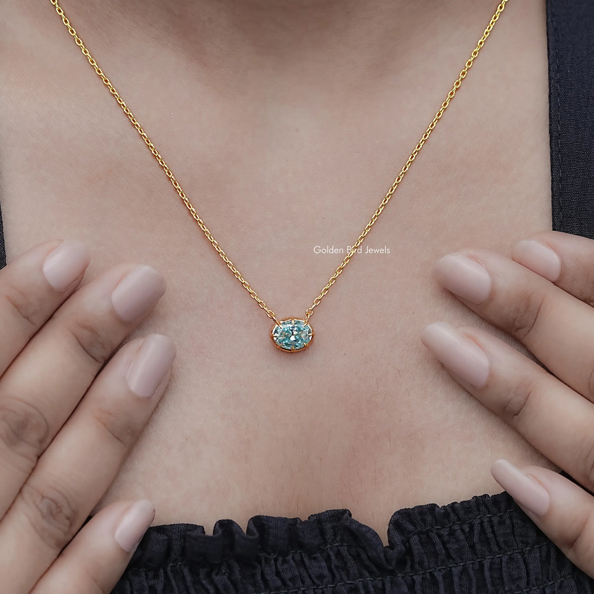 Oval moissanite solitaire pendant necklace with gold-tone chain and blue gemstone center