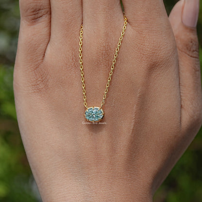 Oval moissanite solitaire pendant necklace on palm with gold-tone chain and blue stone