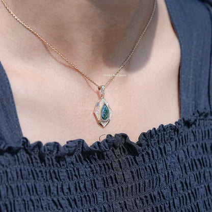 Teal pear-cut moissanite pendant on a fine gold-tone chain over a neckline